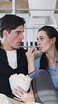 Couple, relax and watching tv with popcorn on sofa with remote control, bonding and talk in home. Man, woman and discussion with choice for movie, film or click for streaming with snacks at apartment