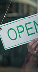 Small business, hands and open sign at cafe window for start of day, customer welcome and retail. Storefront, restaurant manager and signage poster in morning for information and ready for service 
