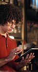 Man, bartender and reading with tablet at bar for inventory, drink menu and stock checklist. Male person, review or digital for online order, sales report and website for beverage price at restaurant