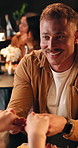 Smile, man and holding hands on date at restaurant with discussion, celebration and anniversary. Couple, laugh and talking with affection, romantic partner and fine dining for relationship commitment