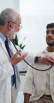 Doctor, man and office with stethoscope for breathe assessment, respiratory exam or advice. People, medical worker and patient in consultation with heartbeat, cardiology evaluation or check lungs