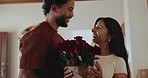 Roses, smell and couple in home with gift, surprise or bonding on valentines day together. Happy, kiss and man with red flowers for woman with romantic present for anniversary in living room of house