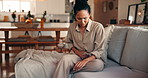 Woman, discomfort and stomach pain on couch at house from menstruation, constipation and cramps. Female person, sore and uncomfortable from appendicitis, gastritis symptoms and chronic endometriosis