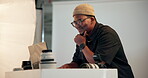 Photographer, man and thinking in studio with laptop, retouching image and creative idea for magazine. Happy, black person or cameraman in agency with computer, color grading and editing photography.