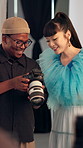 Cameraman, model and talking to woman in studio for photography, show picture or fashion production. Camera, people and conversation on bts set with creative, review image or smile for feedback