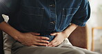 Woman, hands and sick in home with stomach ache, indigestion or inflammation from menstruation cramps. Female person, abdominal pain or discomfort in house with period cycle, IBS or bloating problem.