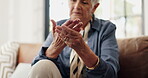Sore, hands and senior woman in lounge, discomfort and pensioner with muscle tension or pain in home. Massage, joint strain and symptoms for arthritis in house, hurt and elderly person with injury