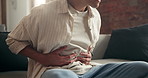 Man, hands and stomach ache with pain on sofa for discomfort, diarrhea or indigestion in home. Male person, tummy bug or sore belly with cramp for gastrointestinal reflux or constipation in house