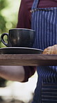 Hands, waiter and coffee with croissant for customer service, hospitality or breakfast in shop. Cafe, server and person carrying latte for drink, food order and walk with morning beverage on tray