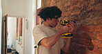 Brick wall, man and drill in home for upgrade, DIY or maintenance with repair for remodeling. Equipment, person and electric machine for drilling, house renovation or improvement with safety goggles