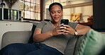 Phone, typing and smile with black woman on sofa for ebook subscription, relax and contact. Digital reading app, online blog and communication with person in living room of home for weekend break