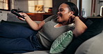 Happy, woman and watching tv with remote on couch, relax or streaming film with subscription in home. Change, channel and black person with smile for entertainment, browsing and resting in lounge