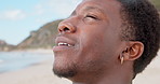 Calm, breathe and black man at beach to relax for wellness, fresh air and reflection on weekend. Nature, happy and person with peace by ocean for inspiration, thinking and stress relief on holiday