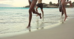 Legs, running and people on beach in waves for summer vacation, holiday and explore for spring break. Happy, weekend and men with women by ocean for freedom, tropical adventure and bonding on trip