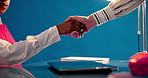 Business people, meeting and studio with handshake for hiring or recruiting on a blue background. Closeup, employees or colleagues shaking hands with tablet for b2b, partnership or onboarding deal