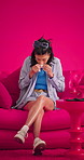Tissue, sneeze and woman on sofa in studio, burnout and influenza symptoms on pink background. Illness, blowing nose and person on couch, disease and allergy season with nasal inflammation and virus