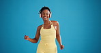 Face, woman and dancing with headphones, fitness and exercise with music, laughing and subscription. Studio, blue background and black person with tech for workout, streaming and happiness in Nigeria