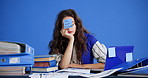 Tired, woman and documents with sticky note in studio for overworked pressure on a blue background. Exhausted, female person or burnout with do not disturb sign for overwhelmed paperwork or fatigue
