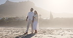 Talk, walk and couple holding hands at beach for love, support and funny joke on vacation. Connection, man and woman travel by ocean for summer holiday, laughing and romance with sunshine on island