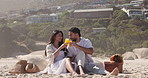 Orange juice, picnic and toast with couple on beach together for anniversary, date or romance. Celebration, cheers and drink with happy people outdoor on coast for holiday, travel or vacation