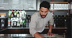 Pub, bartender and cleaning with cloth for hygiene, polish and service for drinks at restaurant. Man, owner and check for dirt with hospitality, shine and cafe with inspection at small business