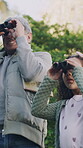 Grandfather, child and search with binocular at park for bird watching, nature observation or knowledge. Learning, grandpa or kid with field glasses for discovery, sightseeing or bonding on low angle