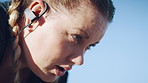 Woman, fitness and break with earphones for workout recovery, intense exercise or training. Active, female person or breathing with sweat, music or blue sky for outdoor rest, health or wellness