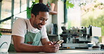 Barista, man and break in coffee shop with phone, social media and notification for text message. Happy, person and worker in cafe with tech, mobile app and browsing website for hospitality trends.
