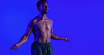 Man, workout and skipping rope in studio with fitness, strength training or intense physical activity. Strong, person and jump exercise with endurance challenge, cardio or wellness on blue background
