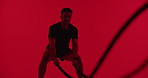 Man, battle ropes and exercise at gym with fitness in studio, equipment or muscle on red background. Person, strength training and intense challenge with cardio, workout and coordination for wellness