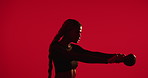 Woman, squat and exercise in studio with kettlebell, strength training or cardio challenge for wellness. Active, person and lifting weights with HIT workout, equipment and fitness on red background.