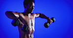 Fitness, weightlifting or man in studio with dumbbells, topless or bicep power in bodybuilding. Intense, space or person with equipment, shirtless workout or muscle transformation on blue background.