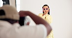 Woman, posing and fashion model with photographer in studio for photoshoot, film set and production. Smile, female person and backstage with cameraman bts, magazine casting and advertising clothes