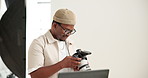Photoshoot, laptop and black man in studio, camera for creative project and entrepreneur. Photographer, freelancer and African person in workplace, pc and equipment for pictures and catalog selection