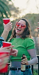 Woman, friends and dancing with alcohol outdoor, social gathering and rhythm at rave party. Bokeh, smile and people with disco ball, listening to music and celebration with energy for festive reunion
