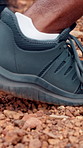 Person, shoe and running with stones on trail for hiking, sprint or outdoor marathon in nature. Closeup, runner or sprinter with sneakers on gravel, dirt track or path for extreme sport or trekking
