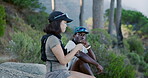 Hikers, eating and couple in woods, break and bonding with partner in nature, adventure and holiday. Outdoor, date and interracial people with food, nutrition and hiking with hydration vest in forest