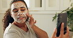 Face mask, phone and tutorial with woman in bathroom of home for cleansing or self care. Facial, skincare and streaming with influencer in apartment to apply antiaging product for wellness routine