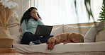 Laptop, yawn and woman on sofa with dog in home for remote work with creative project. Tired, freelancer and female person with puppy pet for bonding in living room with computer in apartment.