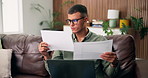 Man, laptop and finance with documents on sofa in home for expenses, bills or bank statements. Male person, checking and reading with paperwork for financial audit, insurance or planning in house