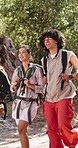 Happy, friends and hiking in forest with backpack, adventure or conversation for bonding together. Bokeh, people smile and trekking outdoor on trail with bag, nature exploration or travel discussion.