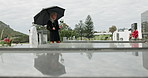 Mourning, graveyard and senior woman by tombstone for loss, death and grief at funeral or memorial service. Ceremony, widow and person with umbrella in cemetery for goodbye, memory and farewell
