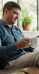 Man, relax and coffee with phone at house to start day, morning routine and browsing website. Male person, blowing and warm beverage with mobile on sofa, social media and notification of text message
