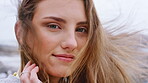 Beach, face and woman with smile in nature, wind and relax on peaceful getaway or traveler on break. Outdoor, travel and person on vacation for adventure, tourist and tourism at sea on weekend in USA