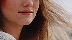 Woman, mouth and hair with wind in nature for natural beauty, freedom or outdoor travel. Closeup, female person or tourist with smile or hairstyle blowing with breeze for haircare or hygiene on beach