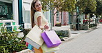 Face, turning and shopping bags with woman on sidewalk in city for energy or satisfaction. Deal, retail sale and spin with happy customer outdoor for celebration of consumerism, discount or purchase
