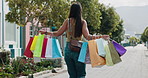 Woman, walking and shopping with bag in city for travel, retail purchase and customer experience. Back, female person and commute outdoor with package for bargain, commercial spree and boutique sales