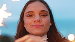 Happy woman, celebration and face at beach with sparklers in evening, birthday and vacation. Girl, memory and portrait with fireworks, success or outdoor on getaway for milestone at seaside in Spain