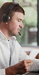 Call center, headset and man in home, talking and advice for customer service, help desk and documents. Remote work, agent or person in lounge, pc or communication for tech support or system solution