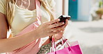 Shopping bags, hands and woman with cellphone in city for texting, social media or chatting. Technology, sale and female person with purchase and phone for networking on mobile app in urban town.